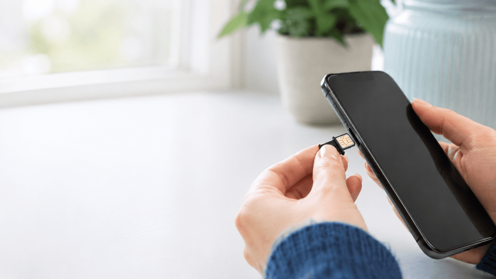 Gros plan sur des mains insérant une carte SIM dans un smartphone